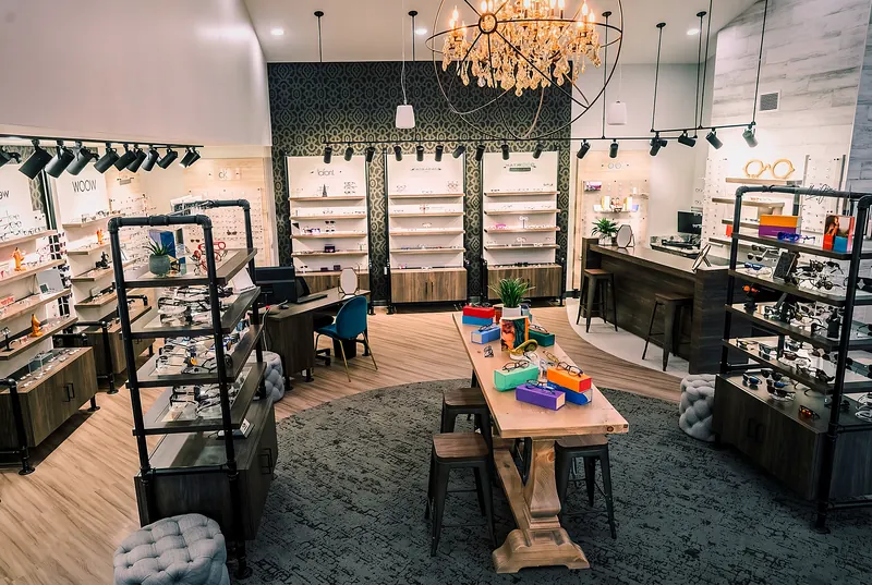 The Haywood Family Eye Care optical: the crystal chandelier over the central fitting table, colorful designer frames filling the displays along both walls