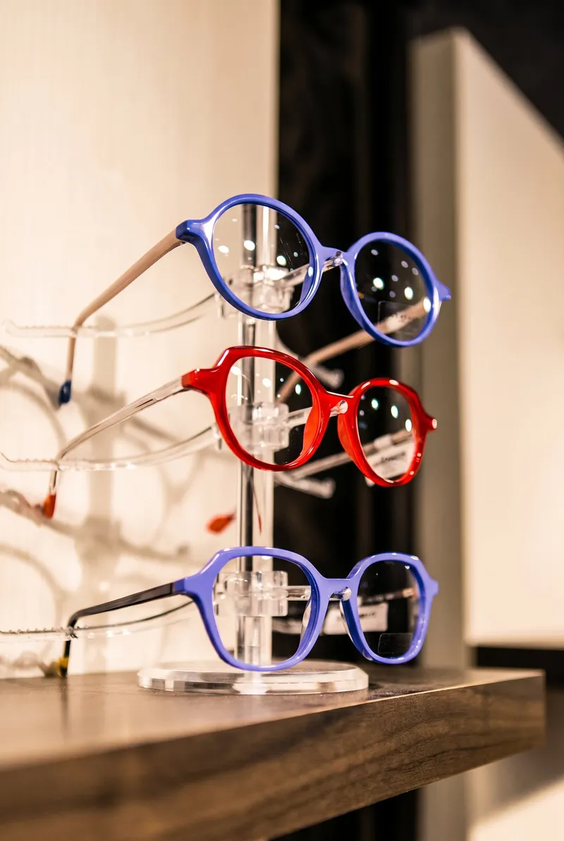 A close-up of blue and red frames on an acrylic stand at the edge of a display shelf